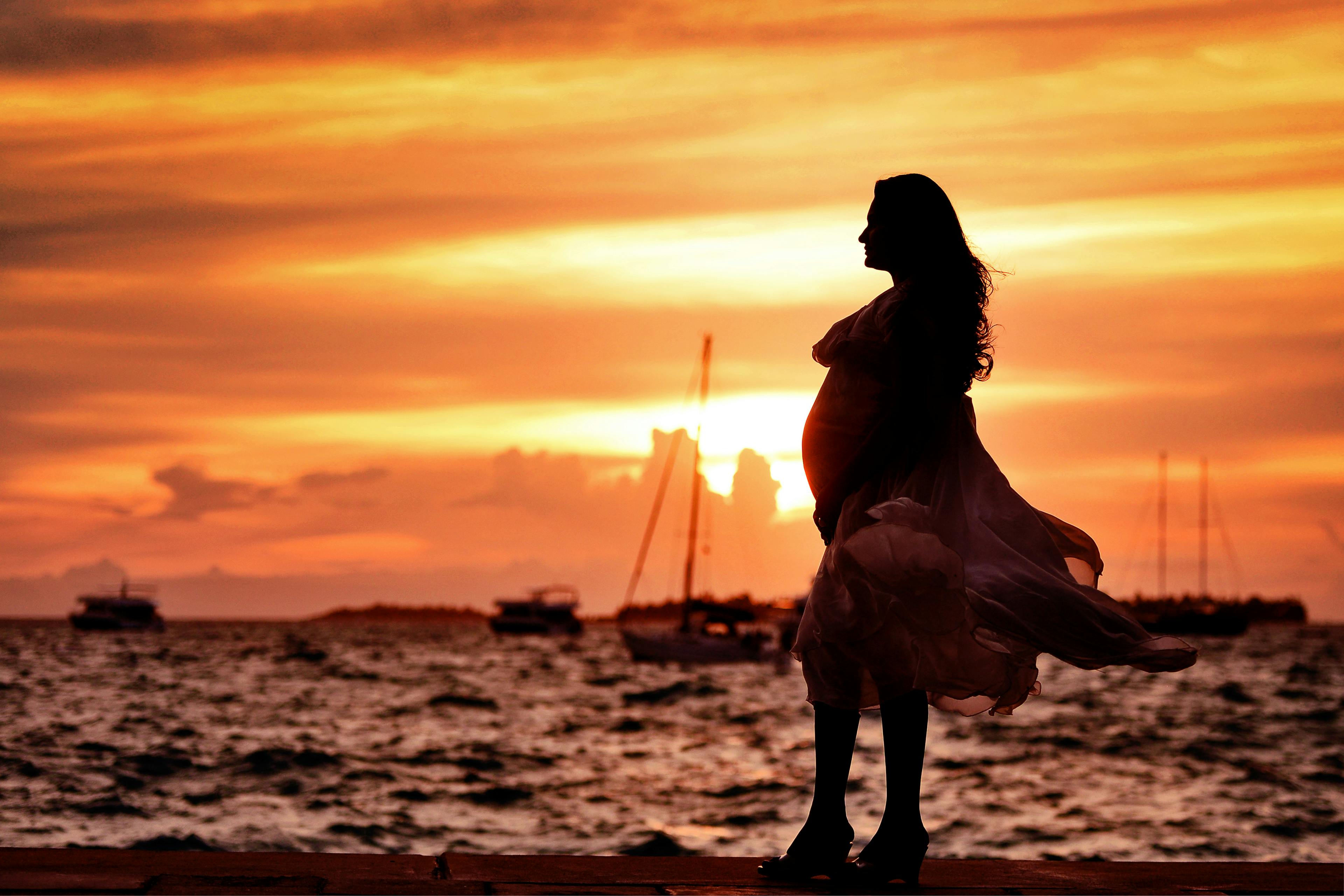 A Pregnant woman standing in the sunset backdrop