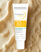 Bioderma Photoderm AKN Mat sunscreen tube on a beige textured background