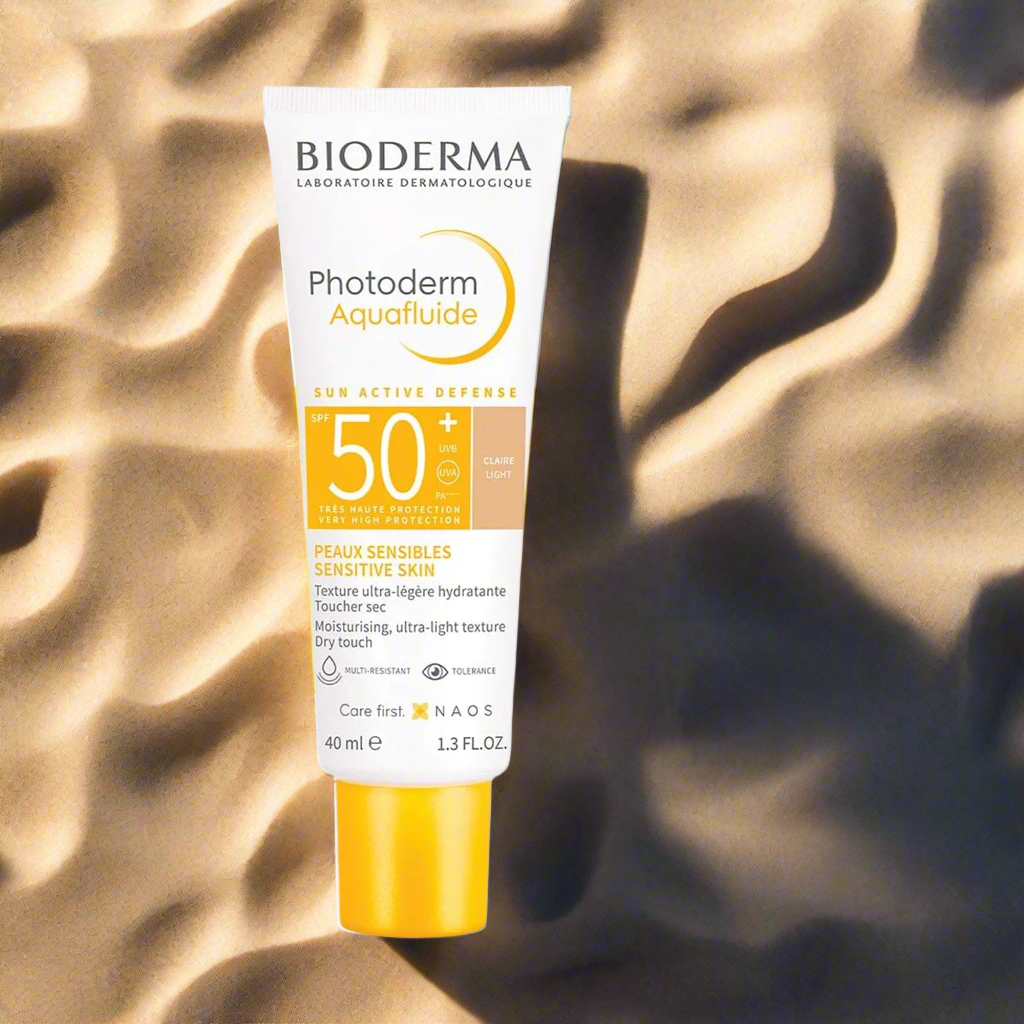Bioderma Photoderm Aquafluide sunscreen bottle on a textured beige background