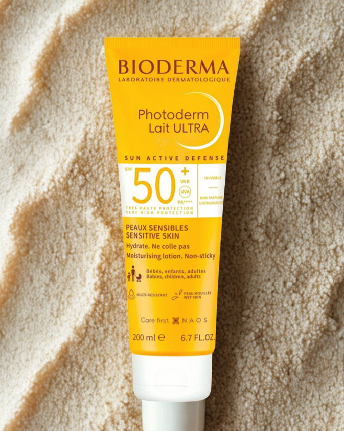 Bioderma Photoderm Lait Ultra sunscreen tube on sand background