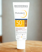 Bioderma Photoderm M sunscreen tube on a wooden surface with a blurred background