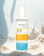 Bioderma Photoderm Pediatrics Spray bottle on a sandy background