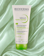 Bioderma Sébium Hydra Cleanser tube on a green fabric background