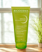 Bioderma Sebium gel moussant actif tube on a windowsill with a plant in the background