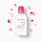 Bioderma Sensibio H2O bottle with pink cap on a white background with rose petals.