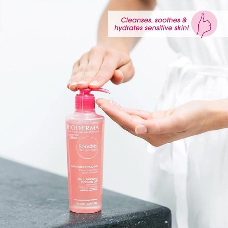 Bioderma Sensibio bottle being held with a hand, on a neutral background