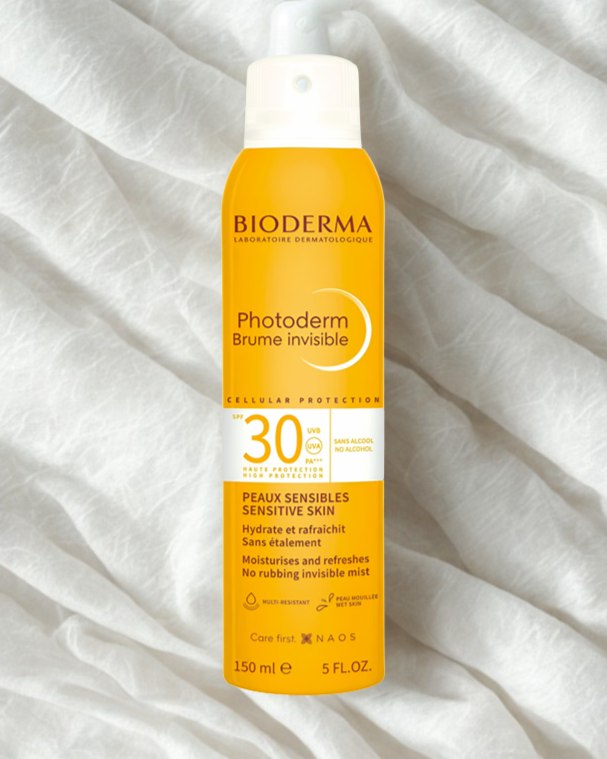 Bioderma sunscreen spray bottle on a white fabric background