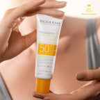Bioderma sunscreen tube held by a hand with a blurred background