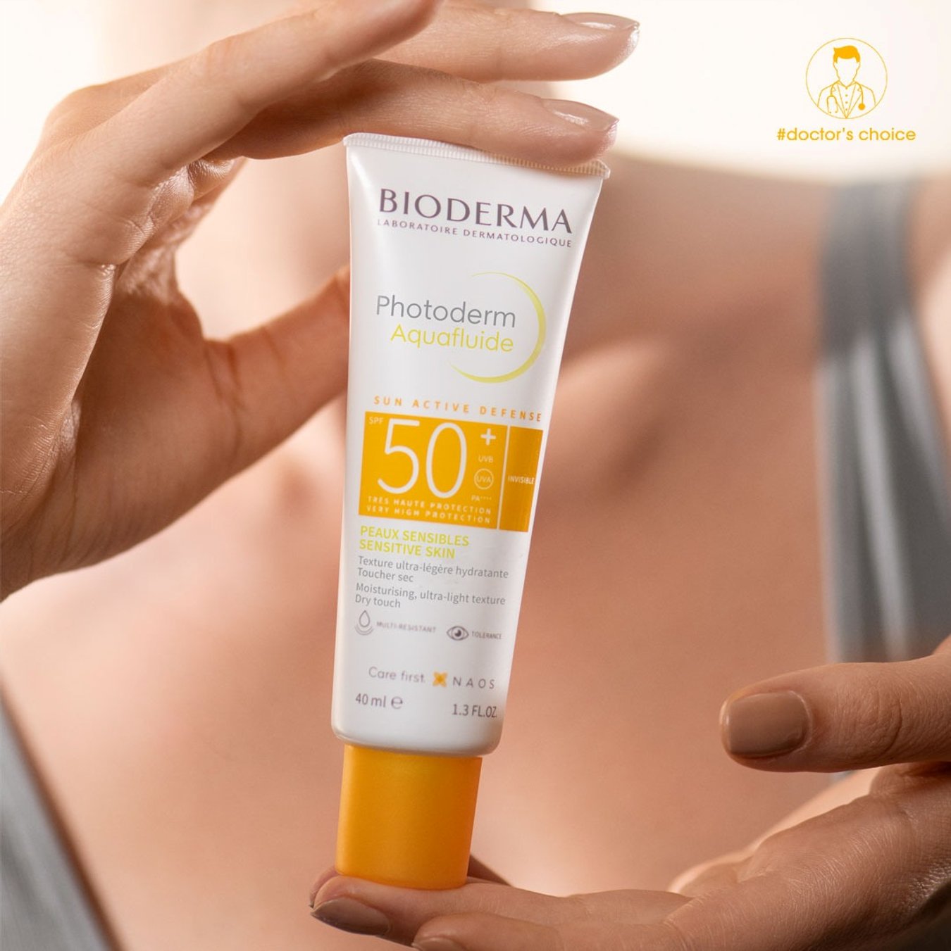 Bioderma sunscreen tube held by a hand with a blurred background