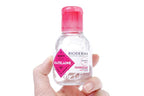 Hand holding a Bioderma bottle with a pink cap on a white background