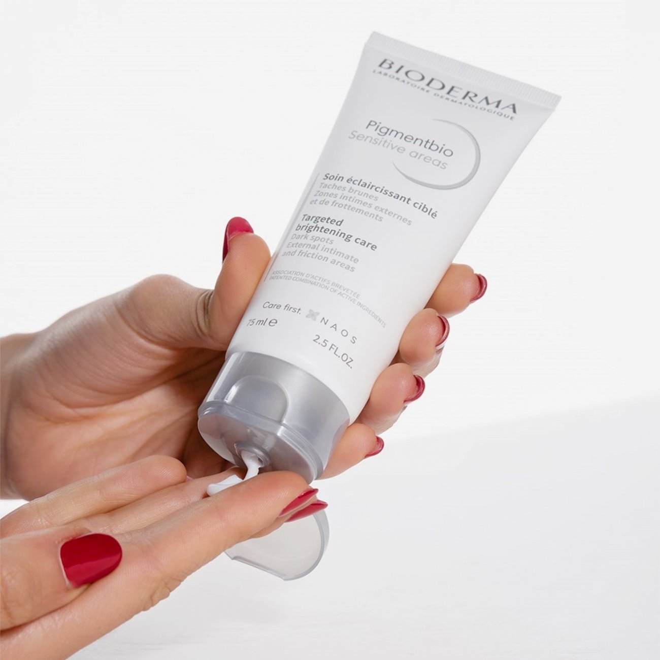 Hand holding a Bioderma skincare product on a white background